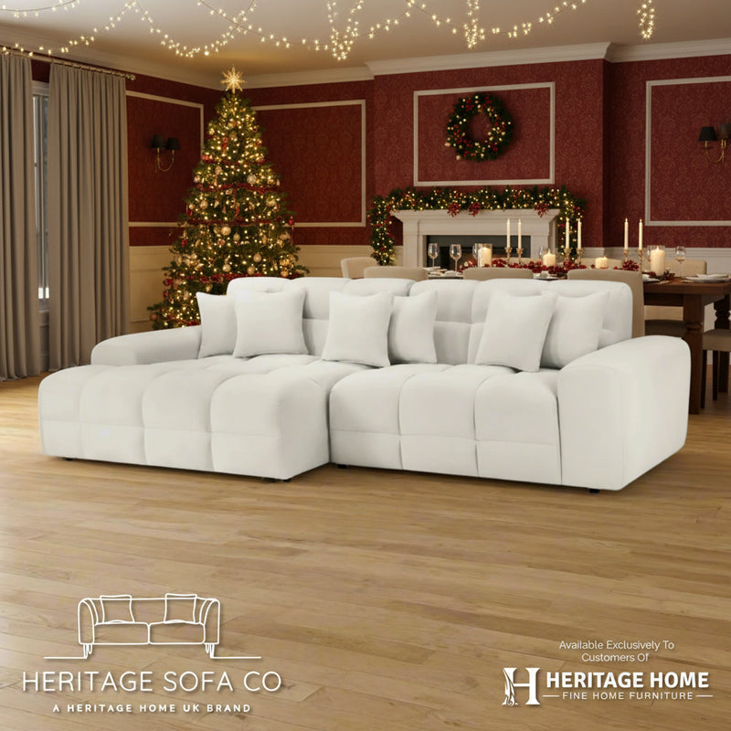 White sectional sofa in a room with wooden flooring and white walls, featuring Heritage Sofa Co branding.