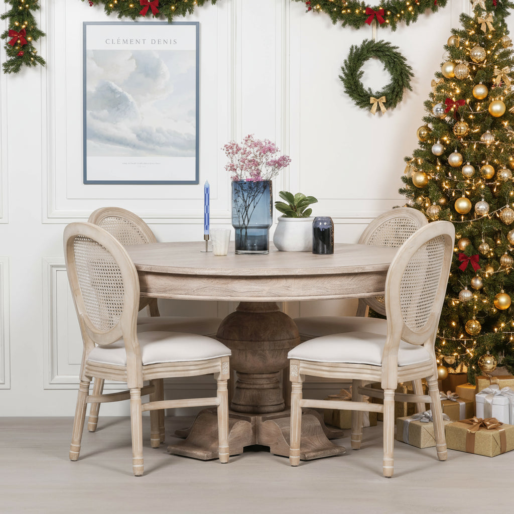 Dining room with a round wooden table and four chairs against a white wall.