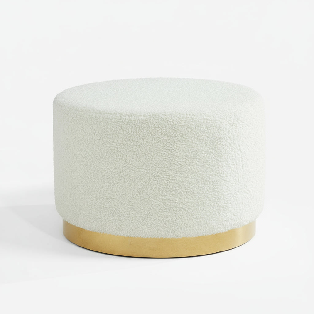 Round white upholstered ottoman with a gold base on a gray floor against a dark paneled wall.Harry Christian Home White Teddy Bear Style Large Footstool or Pouffe With Golden Base 